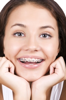 Photo of a pretty young girl smiling with braces on.