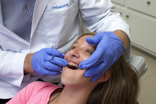 Young girl with traditional braces in orthodontist chair