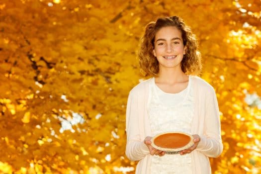 Girl with braces holding a pie on Thanksgiving.