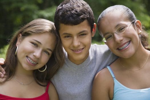 Family of three siblings smiling with braces on