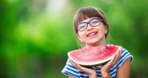 Young girl in braces eating a watermelon