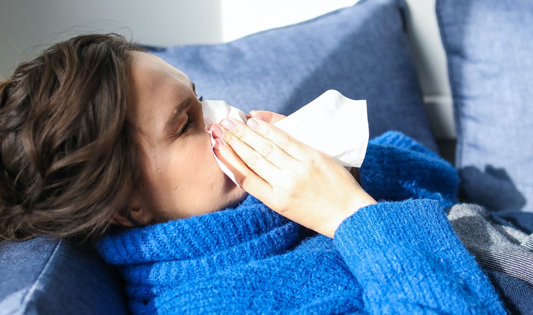 Woman Sick on Couch Blowing her Nose