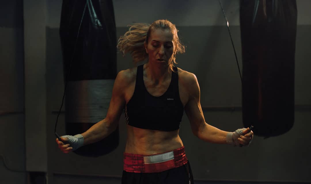 Person with a ponytail jumping rope in a boxing gym