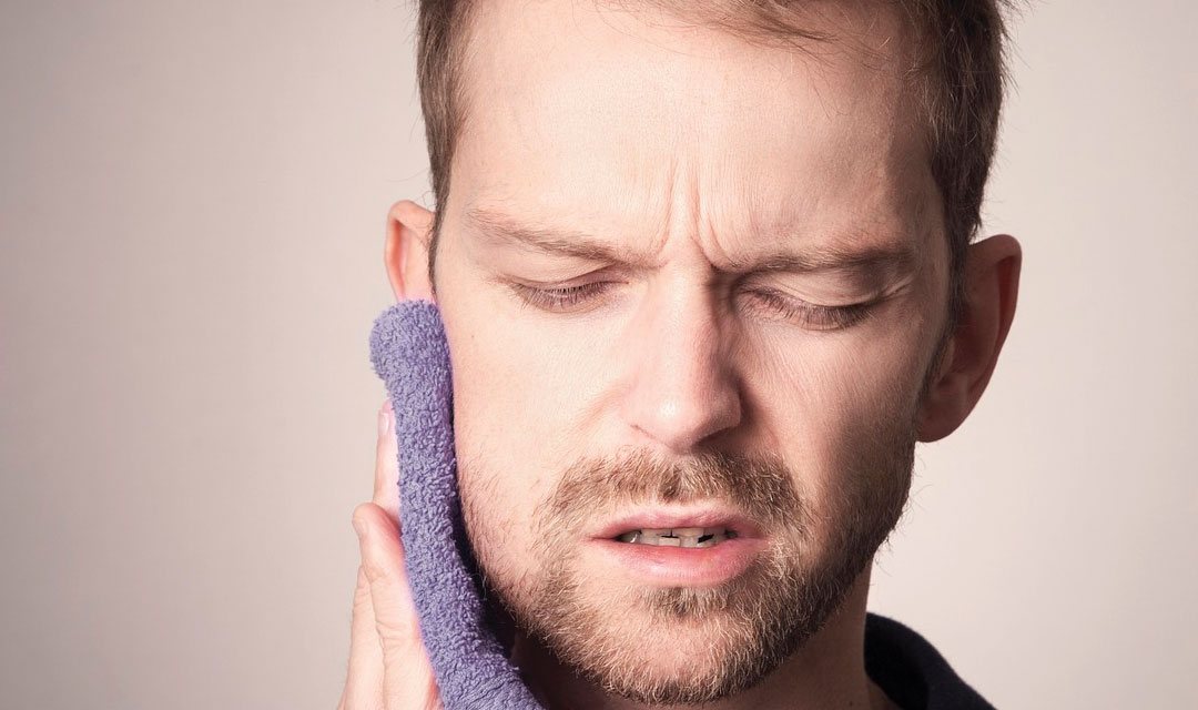 Person in pain holding a compress to their cheek