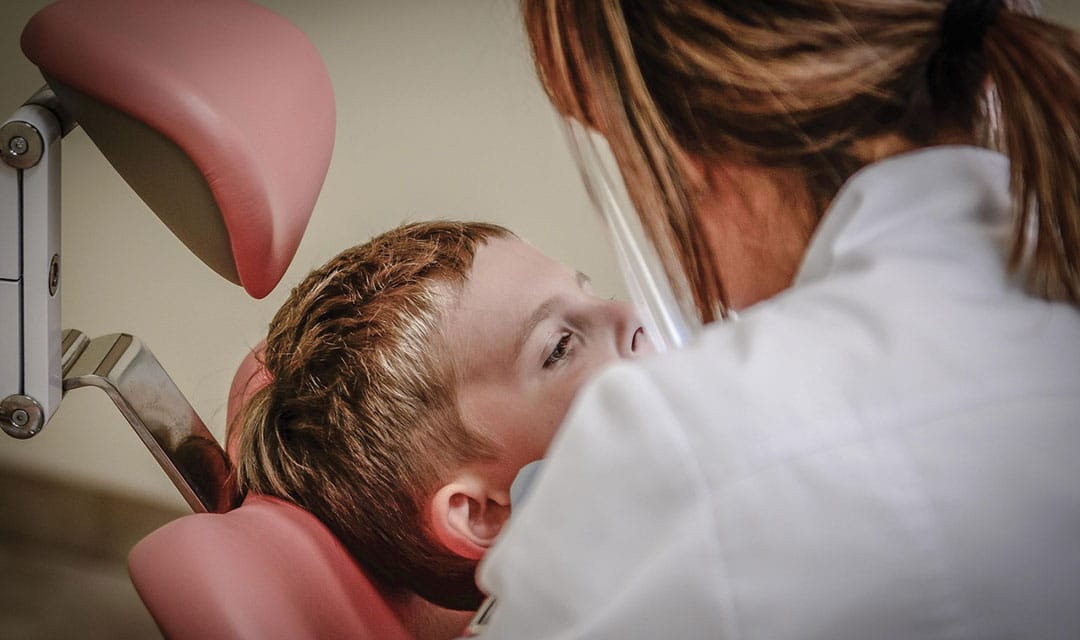Child in a dental chair with a provider talking to them